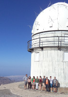Group of students standing in front of a telescope.